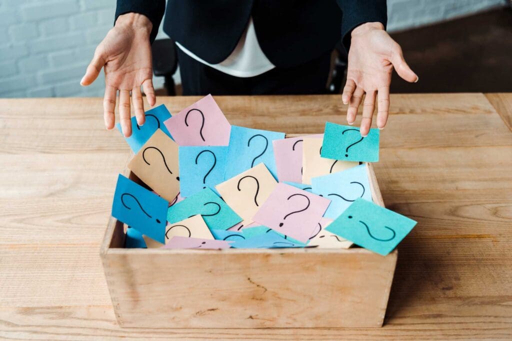 cropped view of woman gesturing near box with question marks on
